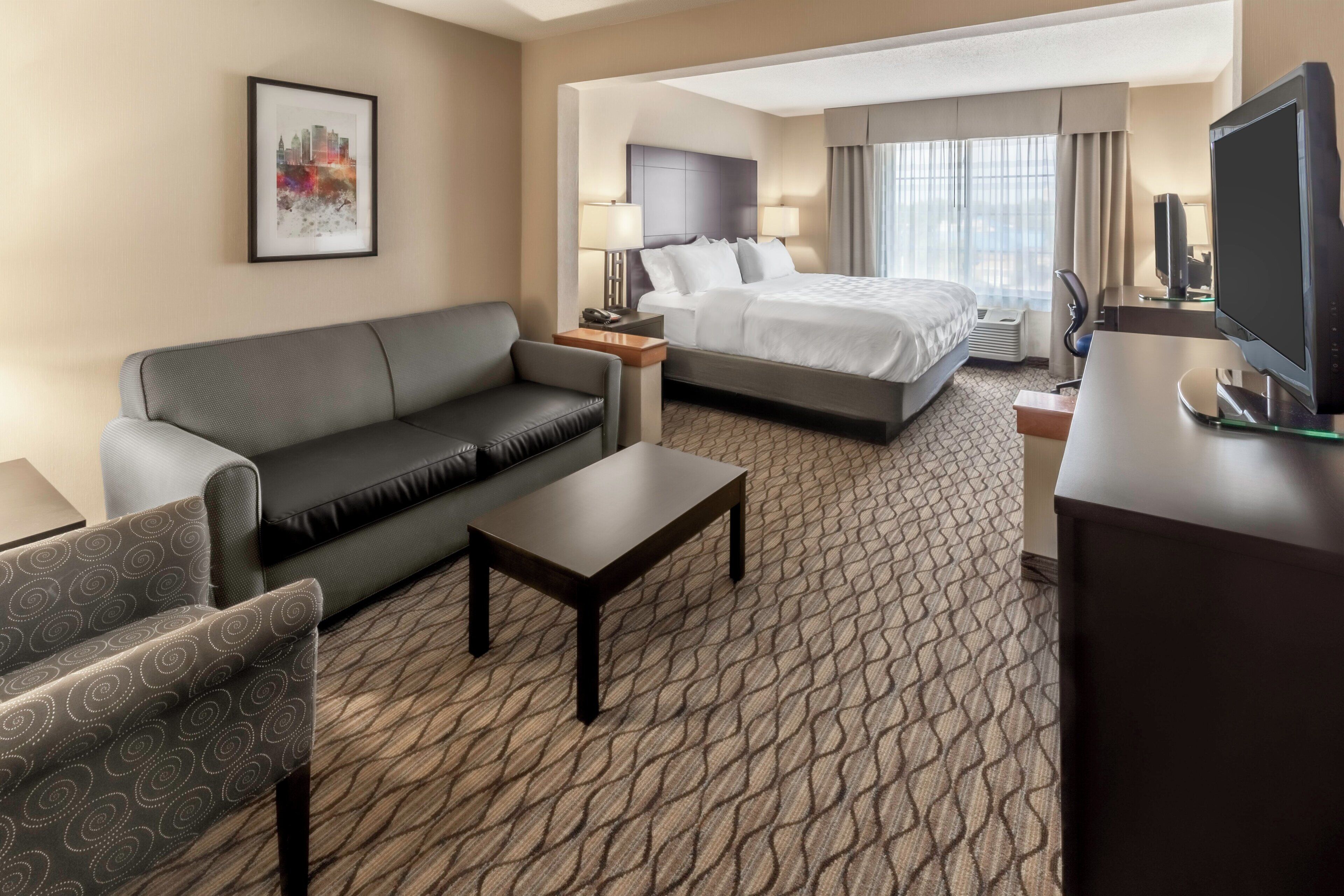 A hotel room with a sofa, a bed, a desk, and a television.