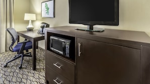 A hotel room with a desk, a chair, a flat-screen TV, a microwave, a lamp, and a framed picture on the wall. - Holiday Inn Hotel & Suites-Milwaukee Airport by IHG (Milwaukee)