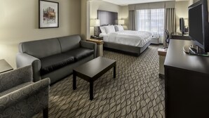 A hotel room with a sofa, a bed, a desk, and a television. - Holiday Inn Hotel & Suites-Milwaukee Airport by IHG (Milwaukee)