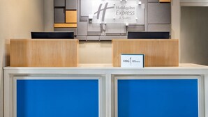 Mostrador de recepción con el cartel de Holiday Inn Express, un marco azul y un cartel que indica IHG One Rewards.