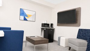 A hotel room with a flat-screen TV, a coffee machine, a microwave, a sofa, a small table, and a decorative wall piece. - Holiday Inn Express Dryden by IHG (Dryden)
