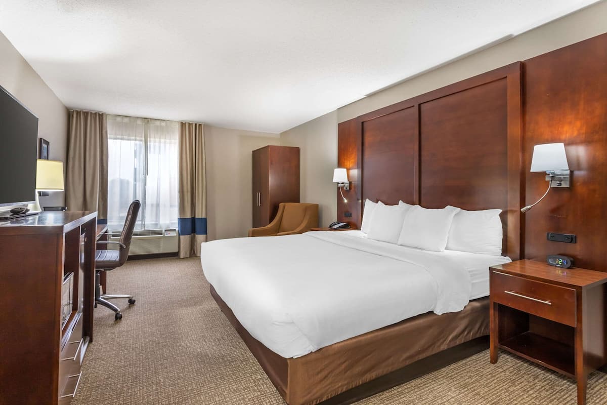 Una habitación de hotel con una cama grande, un escritorio, una silla y un armario.