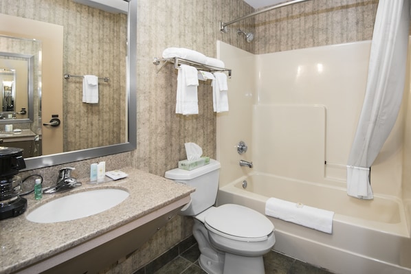 A bathroom with a sink, toilet, and bathtub. There are towels hanging on a rack and a shower curtain.