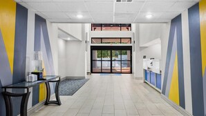 A hallway with a double door, a reception desk, and a tiled floor.