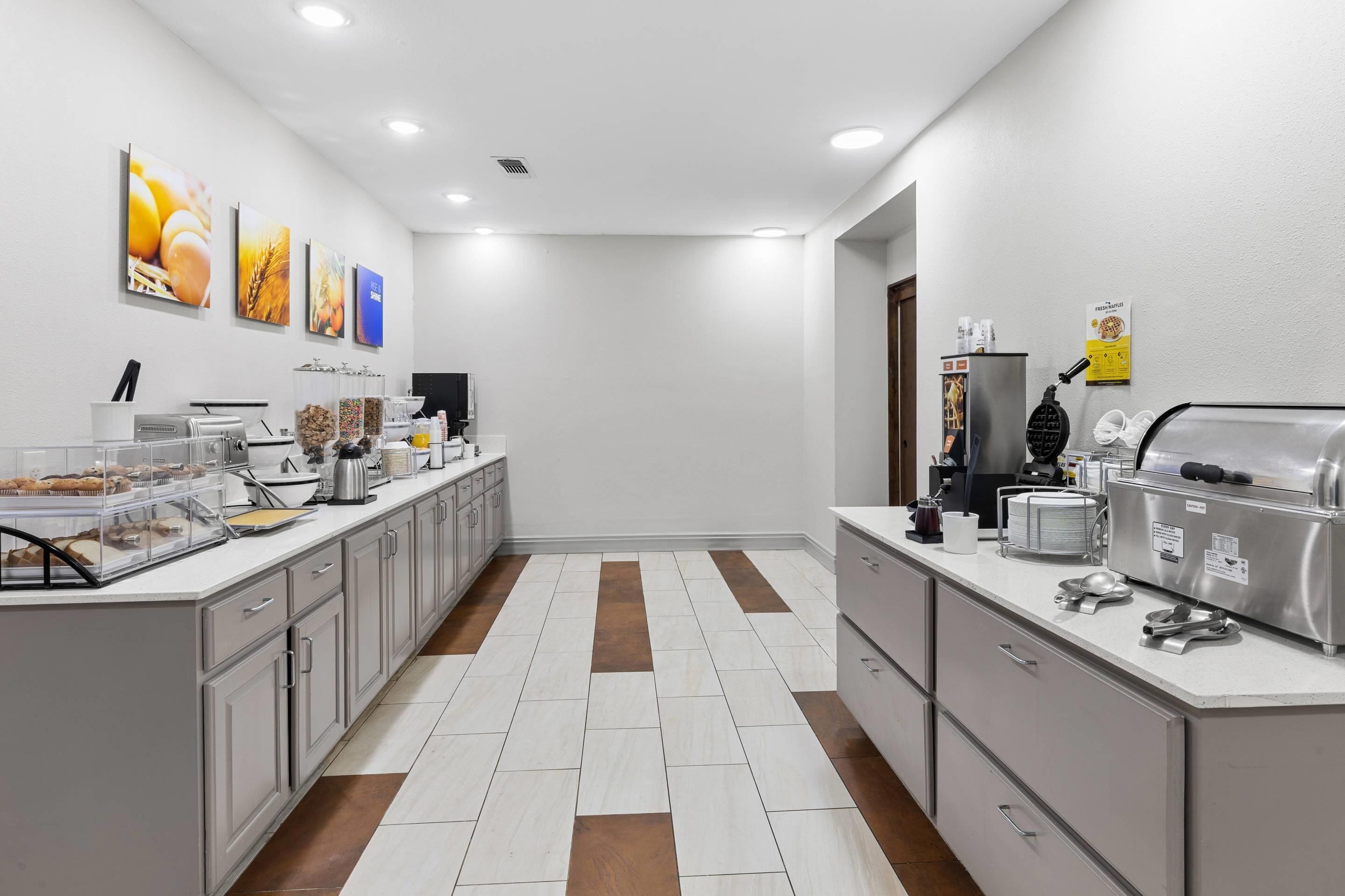Una cocina moderna con piso de baldosas blancas y marrones, electrodomésticos de acero inoxidable y una cafetera.