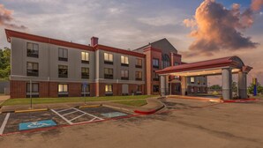 A multi-story hotel with a brick facade, a covered parking area, and handicap-accessible parking spaces.