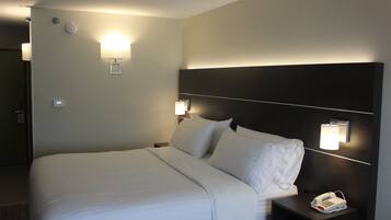 Habitación de hotel con una cama grande, dos lámparas de noche, una mesita con teléfono y una lámpara de pared.