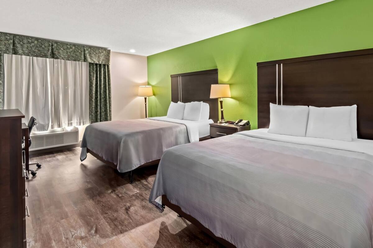 Habitación de hotel con dos camas, un escritorio y una silla.
