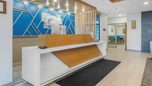 A reception desk with a modern design, a blue geometric wall, and a wooden accent.