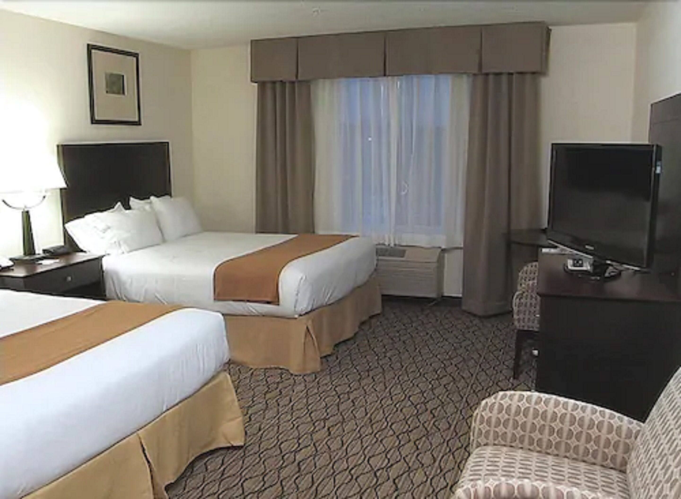 Une chambre d’hôtel avec deux lits, une télévision, un bureau et une chaise.