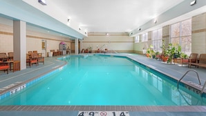 An indoor swimming pool with a 49'9' depth, surrounded by lounge chairs and potted plants. - Holiday Inn Express St. Croix Valley by IHG (St Croix Falls)