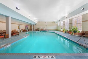 An indoor swimming pool with a 49'9' depth, surrounded by lounge chairs and potted plants. - Holiday Inn Express St. Croix Valley by IHG (St Croix Falls)