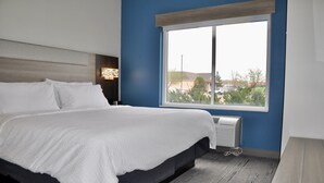 A modern hotel room with a large bed, a window with a view of the outside, and a built-in air conditioning unit. - Holiday Inn Express St. Croix Valley by IHG (St Croix Falls)
