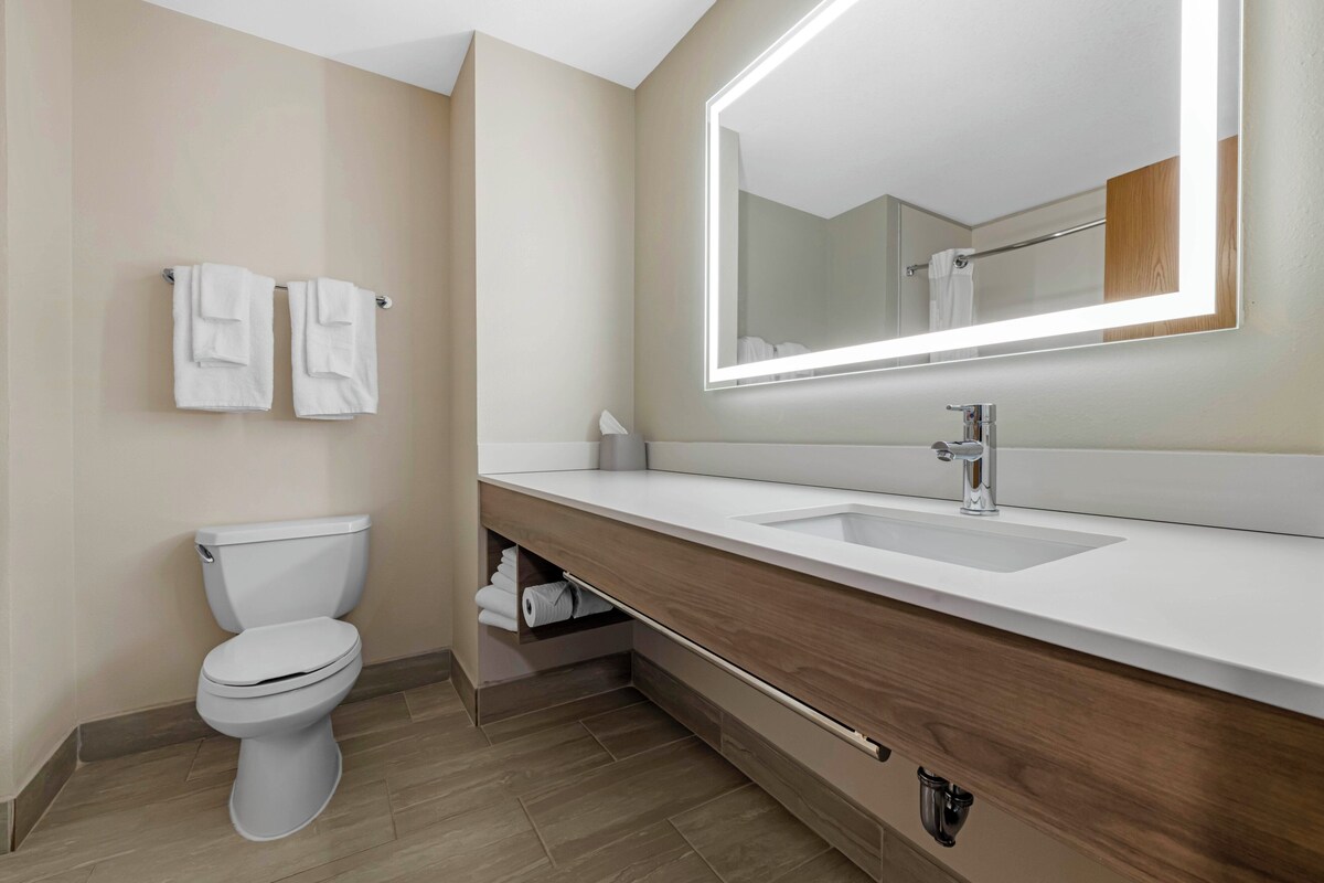 A modern bathroom with a toilet, sink, mirror, and towel rack.