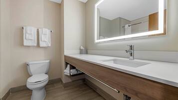 A modern bathroom with a toilet, sink, mirror, and towel rack.