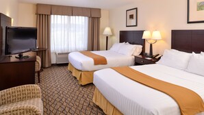 A hotel room with two beds, a TV, a desk, and a chair.