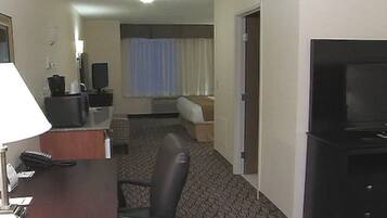 A hotel room with a desk, chair, television, and a bed.