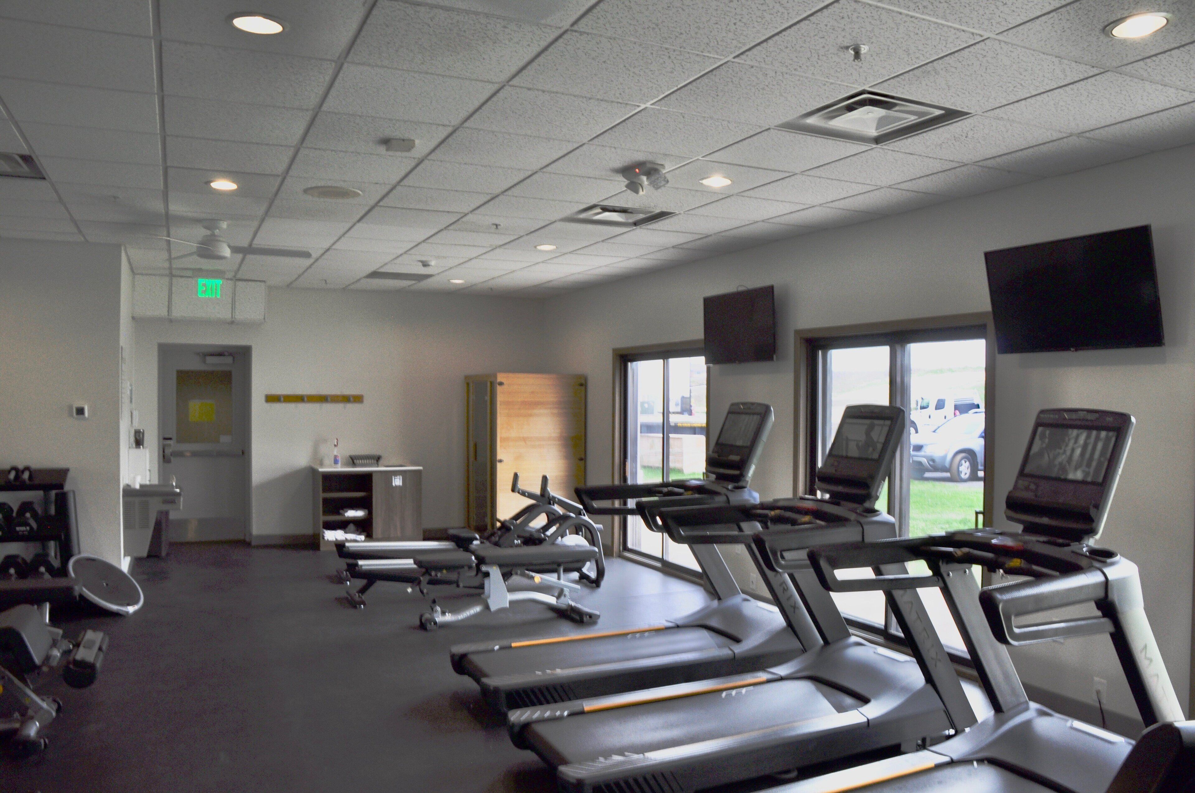 A gym with treadmills, weights, and a large window.