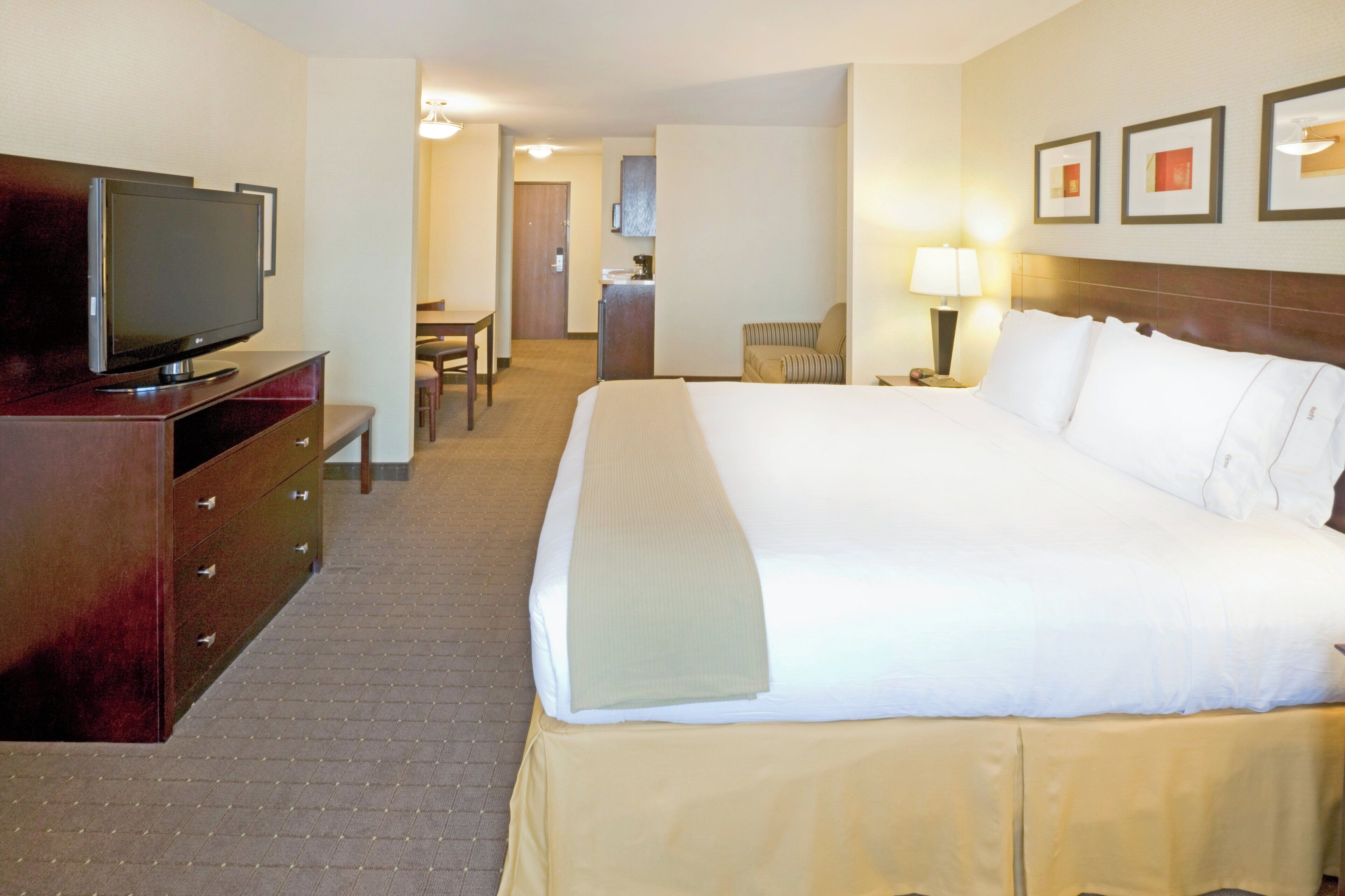 Una habitación de hotel con una cama, un televisor en una cómoda, un escritorio y una silla.