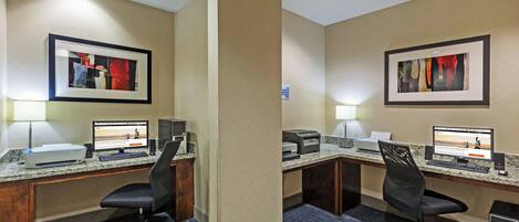 Habitación de hotel con dos escritorios, cada uno equipado con una computadora, impresora y lámpara de escritorio.
