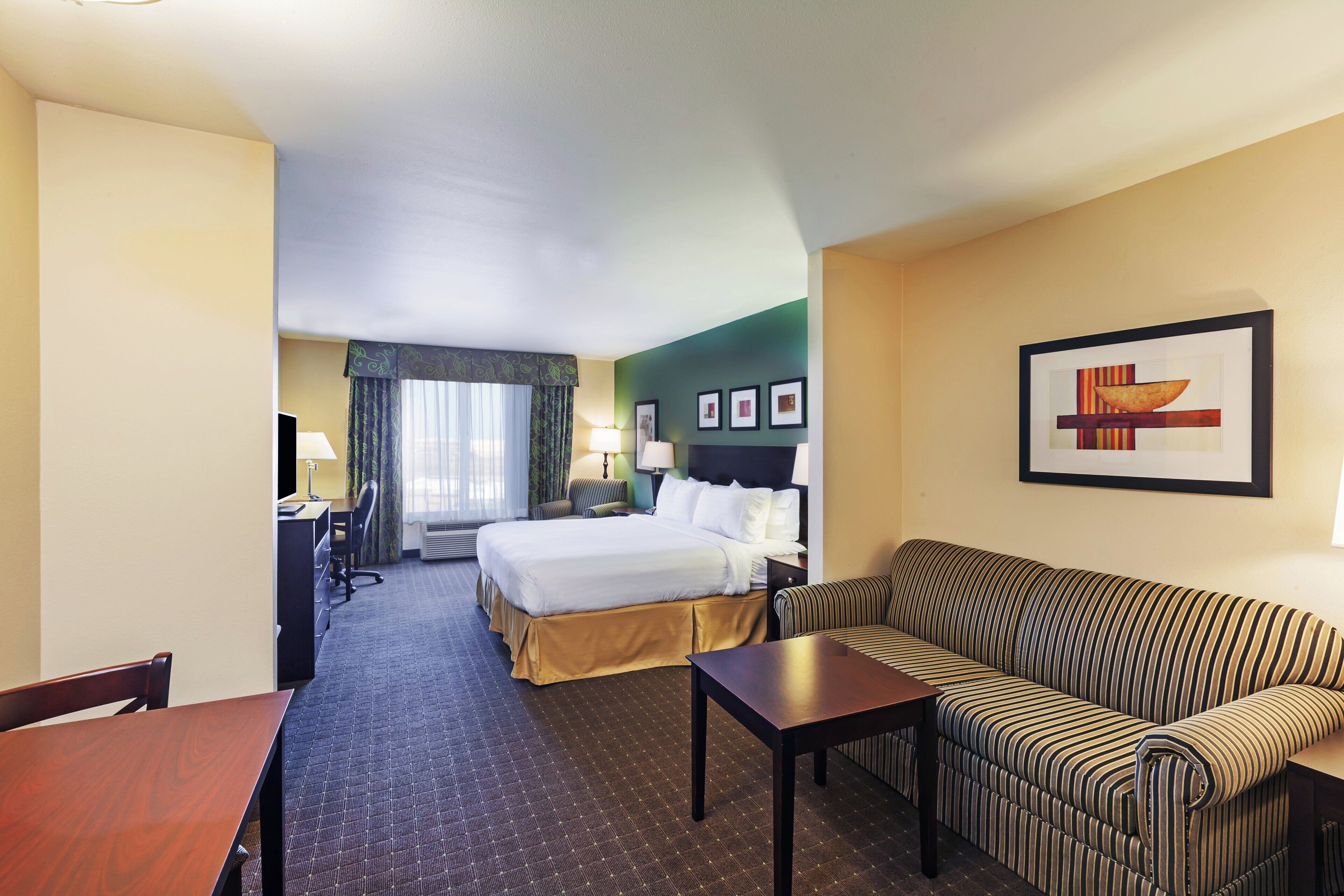 A hotel room with a bed, a sofa, a desk, and a chair.