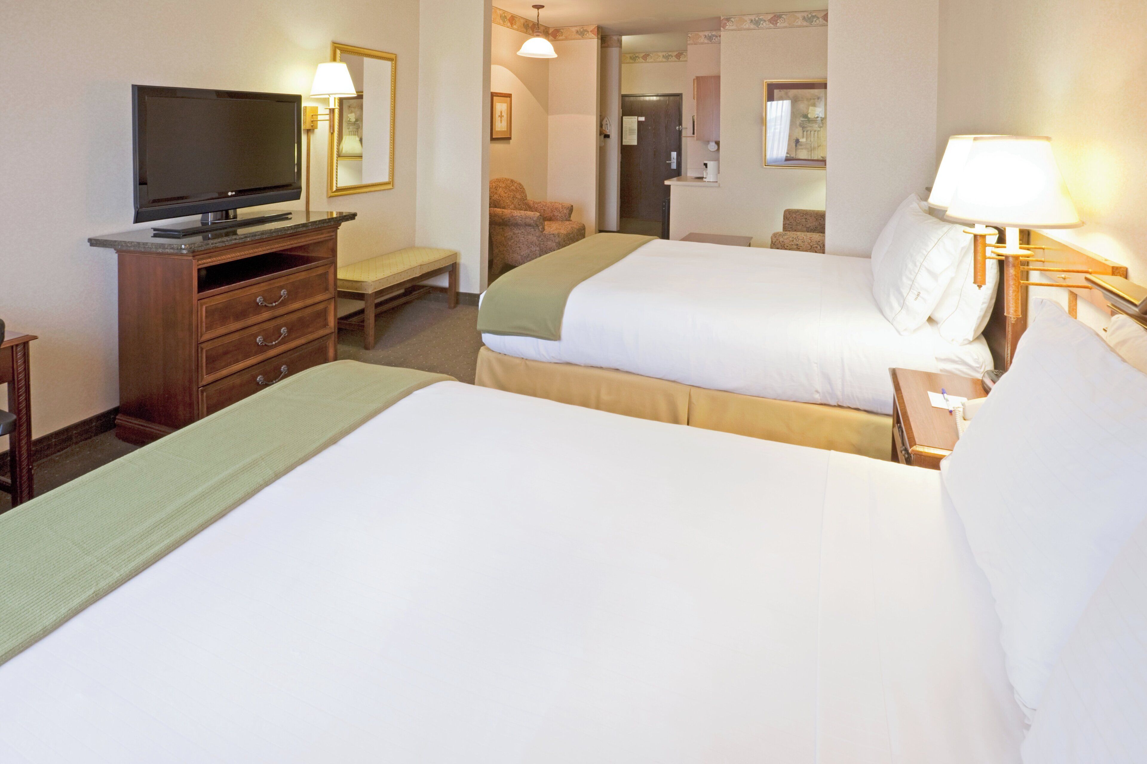 A hotel room with two beds, a television, a desk, and a chair.