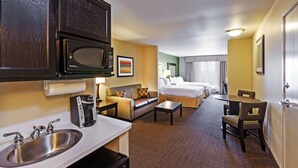 A hotel room with a kitchenette, a bed, a sofa, a dining table, and a small bathroom. - Holiday Inn Express & Suites Eagle Pass by IHG (Eagle Pass)