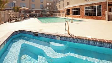 Une piscine avec un bord carrelé, un plongeoir et des chaises longues.