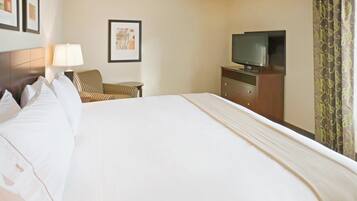 Habitación de hotel con una cama grande, un televisor sobre una cómoda, una silla y una lámpara.