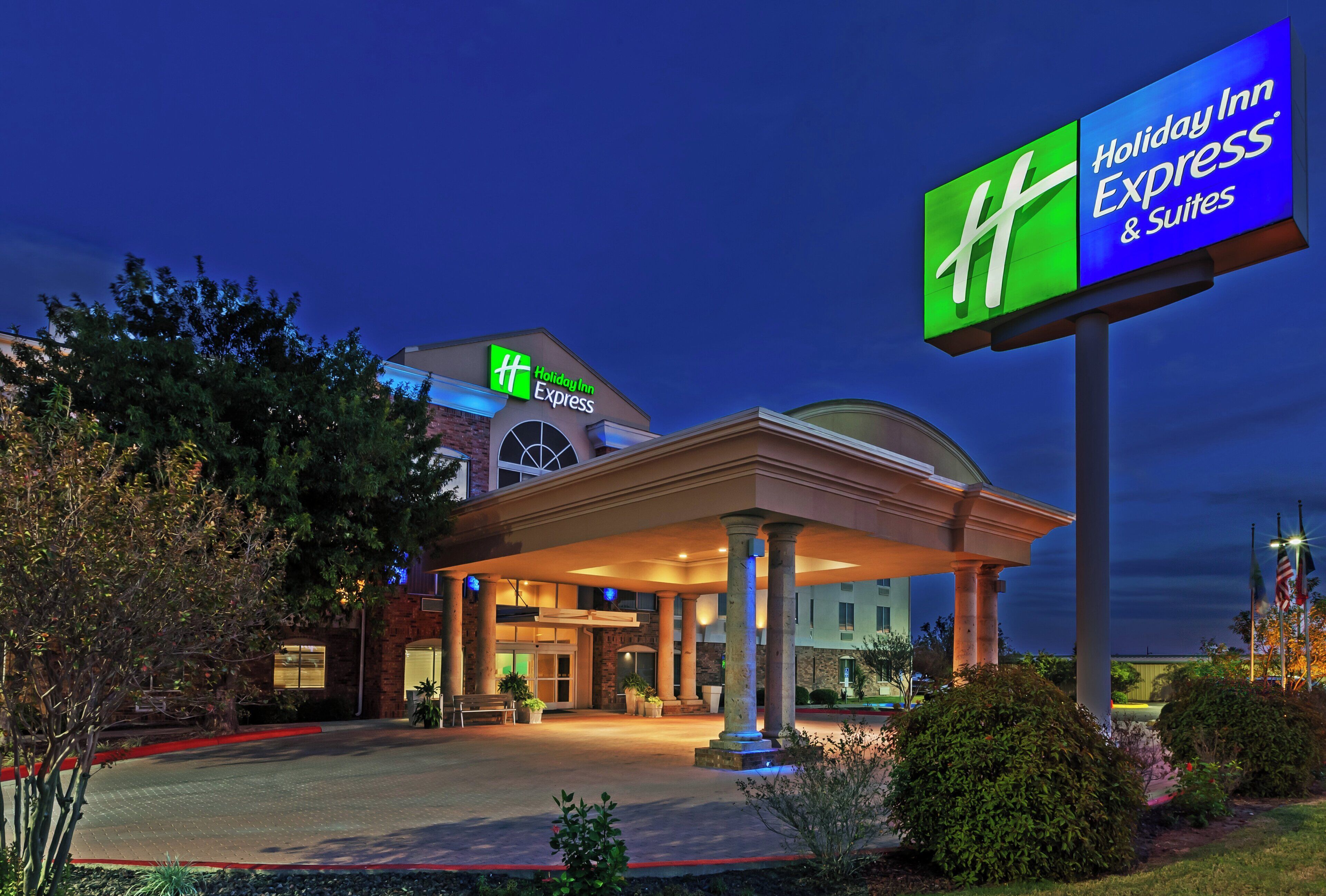 A Holiday Inn Express & Suites building with a prominent sign, a covered entrance, and a landscaped front area.