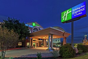 A Holiday Inn Express & Suites building with a prominent sign, a covered entrance, and a landscaped front area.