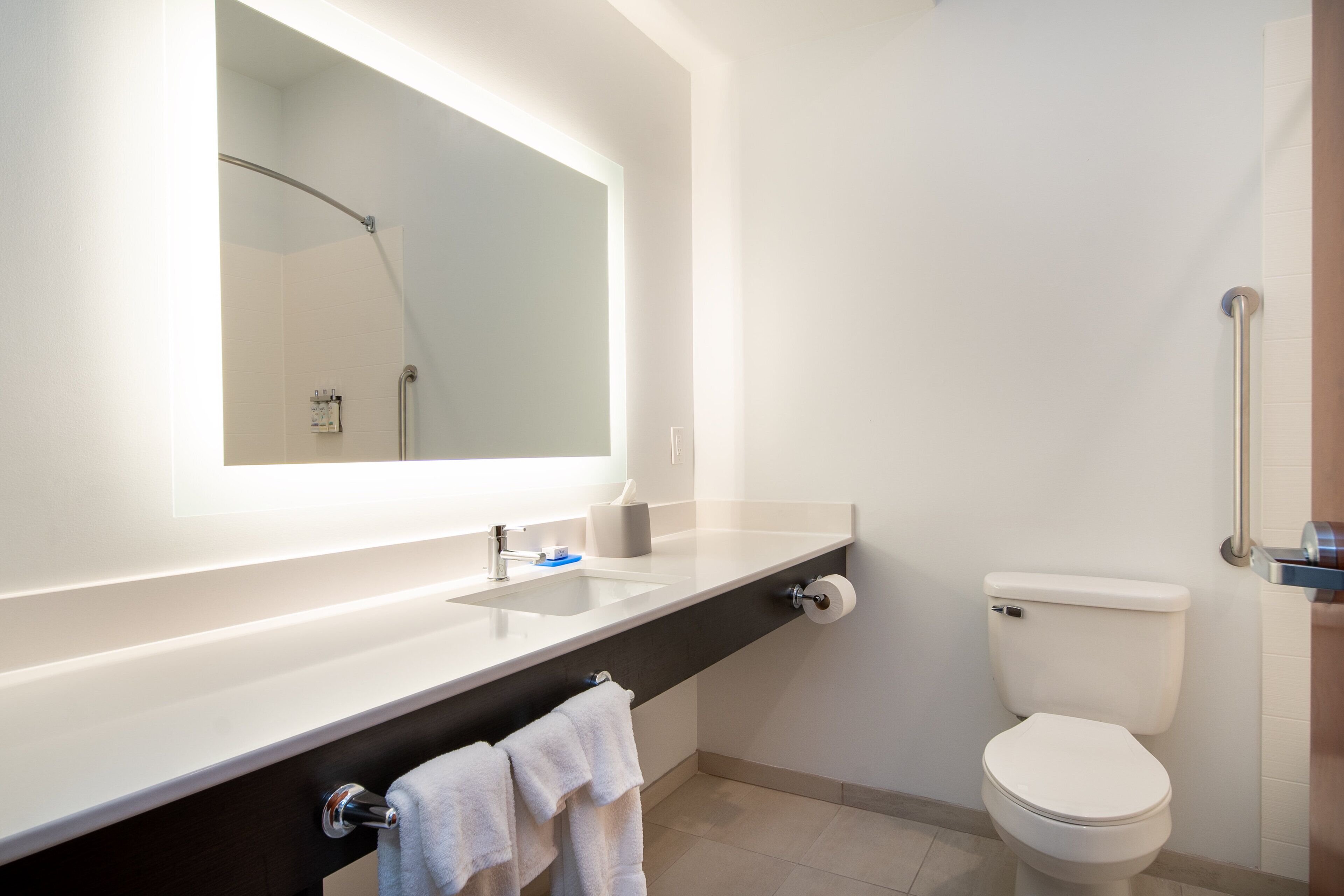 Une salle de bain moderne avec un lavabo blanc, un miroir et des toilettes.