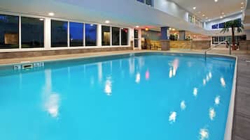 Une piscine intérieure à l’eau claire, dotée d’un plongeoir et entourée d’un mur en pierre.