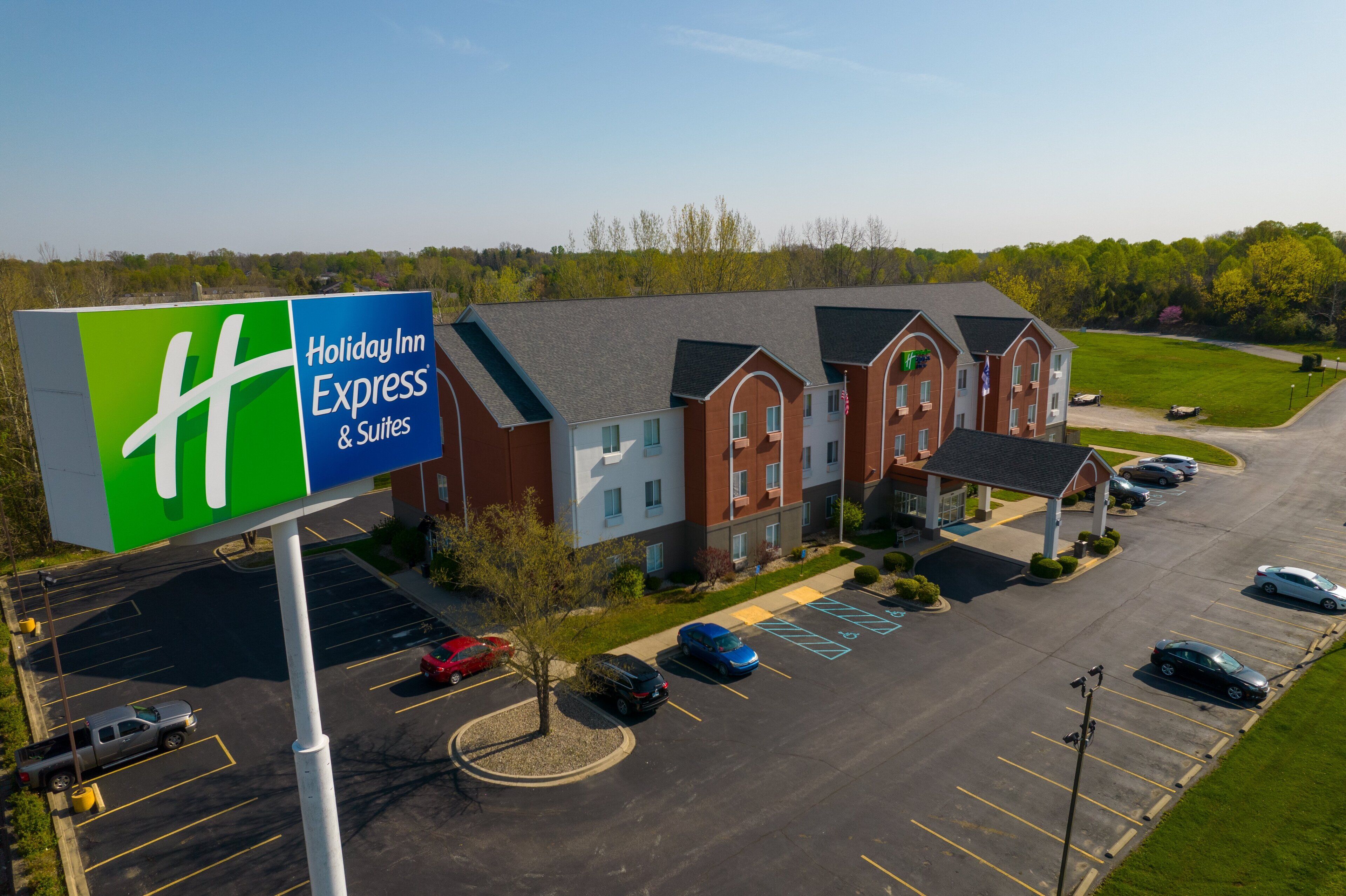 A Holiday Inn Express & Suites with a large sign, a parking lot, and a building with multiple units.