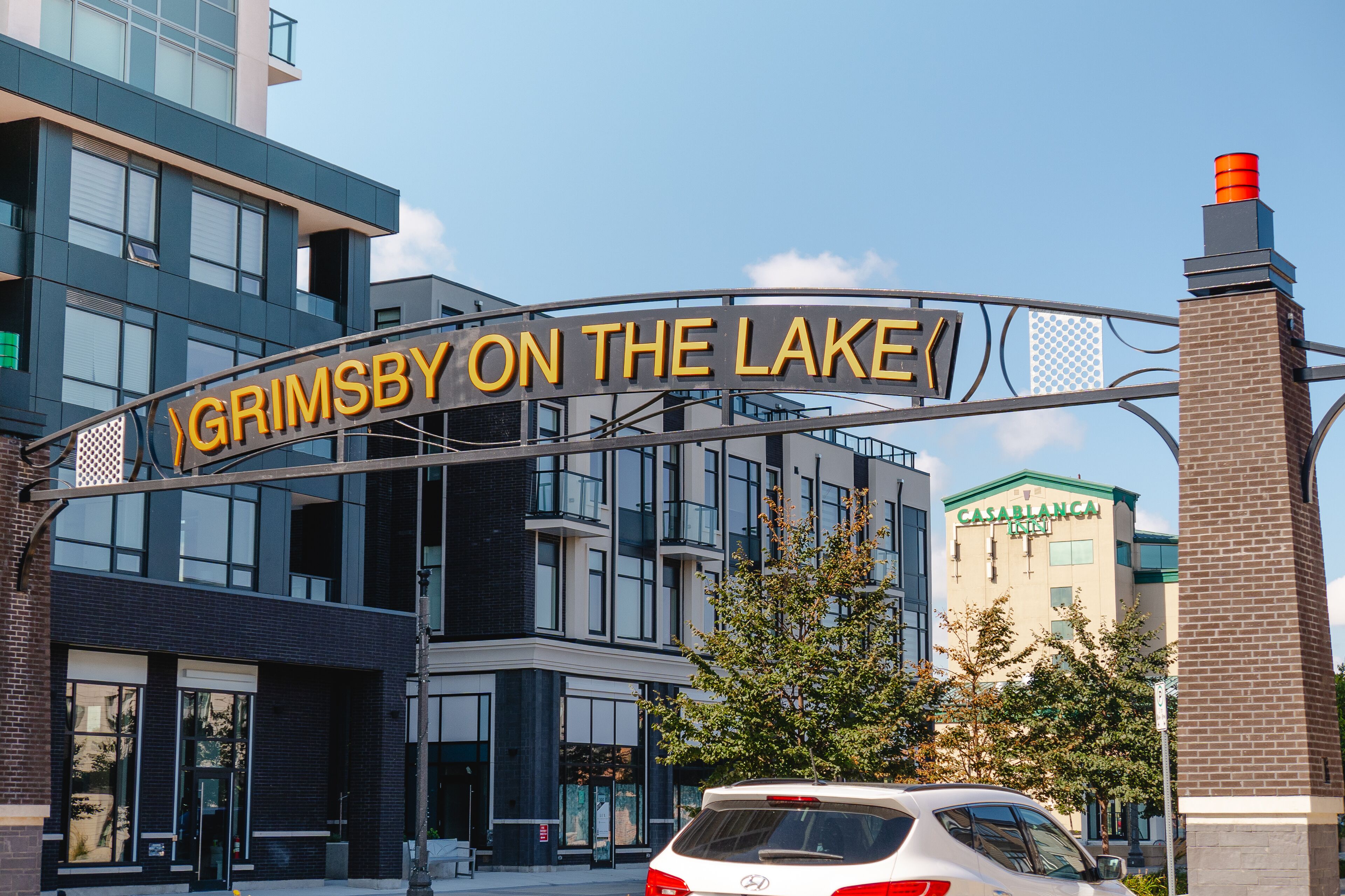 A sign reading "Grimsby on the Lake" with modern buildings in the background.