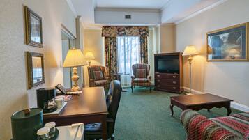 Habitación de hotel con una mesa de comedor, dos sillones, un sofá, un televisor y una chimenea.