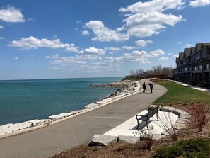 A coastal walkway with a bench, a clear view of the sea, and a row of modern buildings in the background. - The Casablanca Hotel (Grimsby)