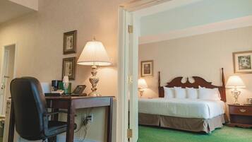A hotel room with a bed, bedside tables, a desk with a lamp, and a chair.