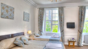 A hotel room with two beds, a television, and a window with curtains. - The Bedford Hotel (Tavistock)
