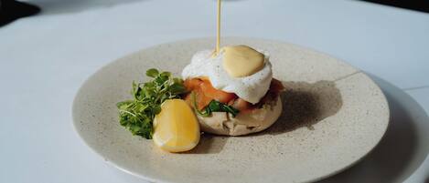 A breakfast dish on a plate with a candle in the background.