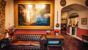 A room with a large framed painting, a leather sofa, a wooden coffee table, and a red carpeted floor. - The Bedford Hotel (Tavistock)