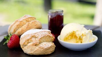 A dessert plate with scones and a scoop of ice cream, accompanied by a strawberry and a jar of jam.