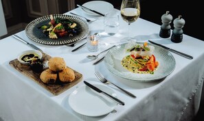 A table set for a meal with plates of food, a glass of wine, and salt and pepper shakers. - The Bedford Hotel (Tavistock)