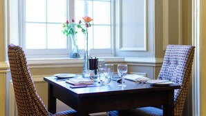 A dining table set with glassware, plates, and a vase with flowers. - The Bedford Hotel (Tavistock)