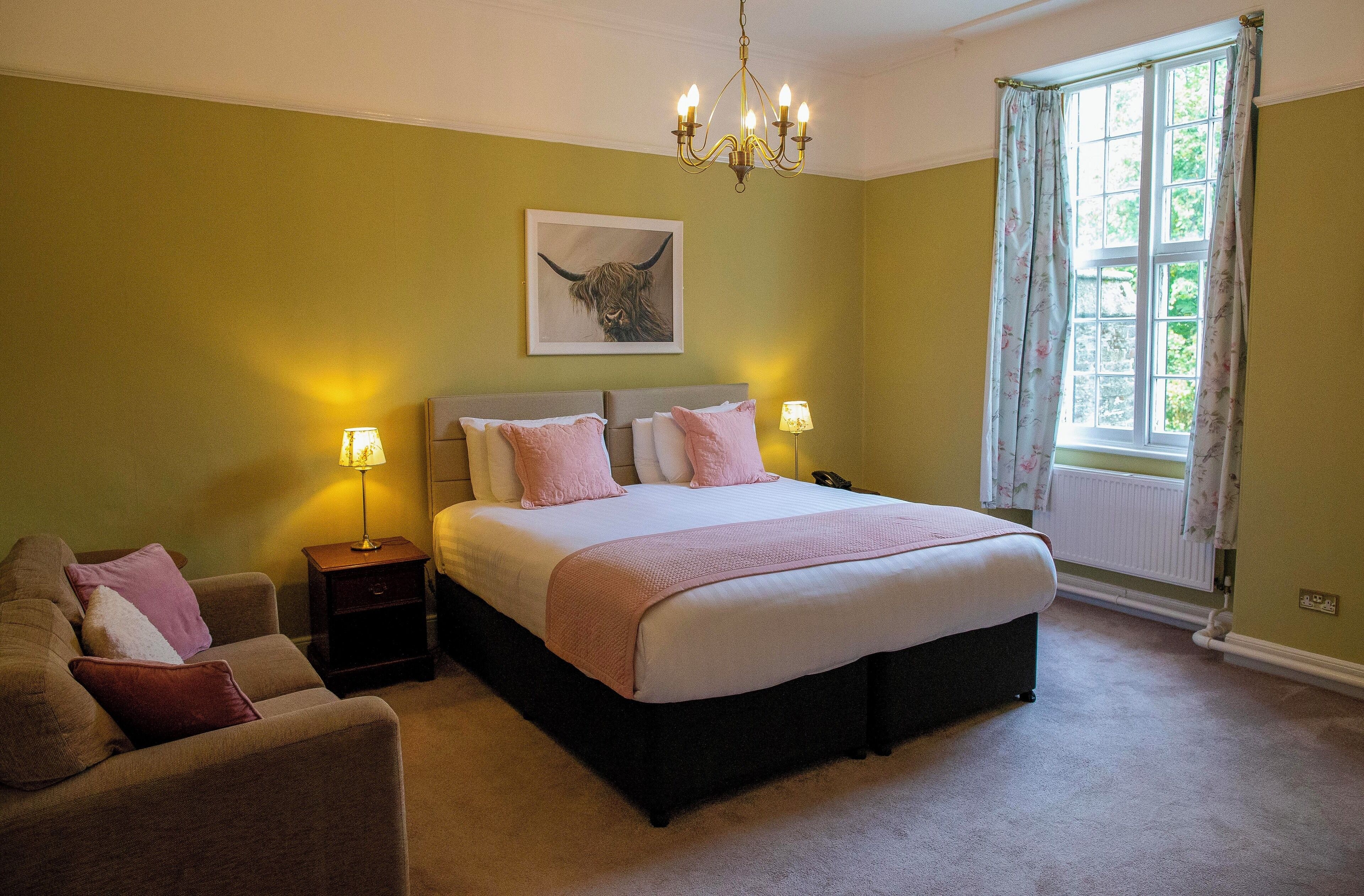 Een slaapkamer met een groot bed, nachtlampjes, een bank en een kroonluchter.