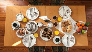 Una tavola apparecchiata per la colazione con piatti, tazze e diversi cibi.