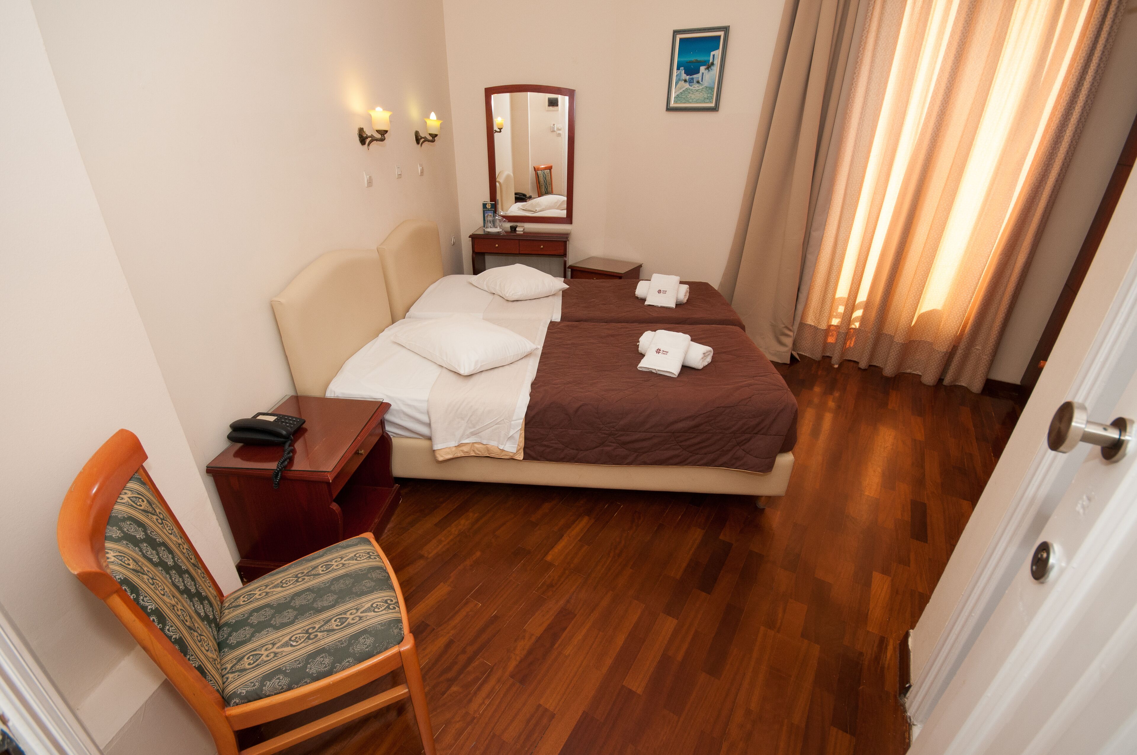 A hotel room with a bed, bedside table, chair, and a mirror.