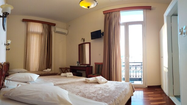 Una camera d'albergo con due letti, una scrivania, una sedia, una televisione e un balcone.