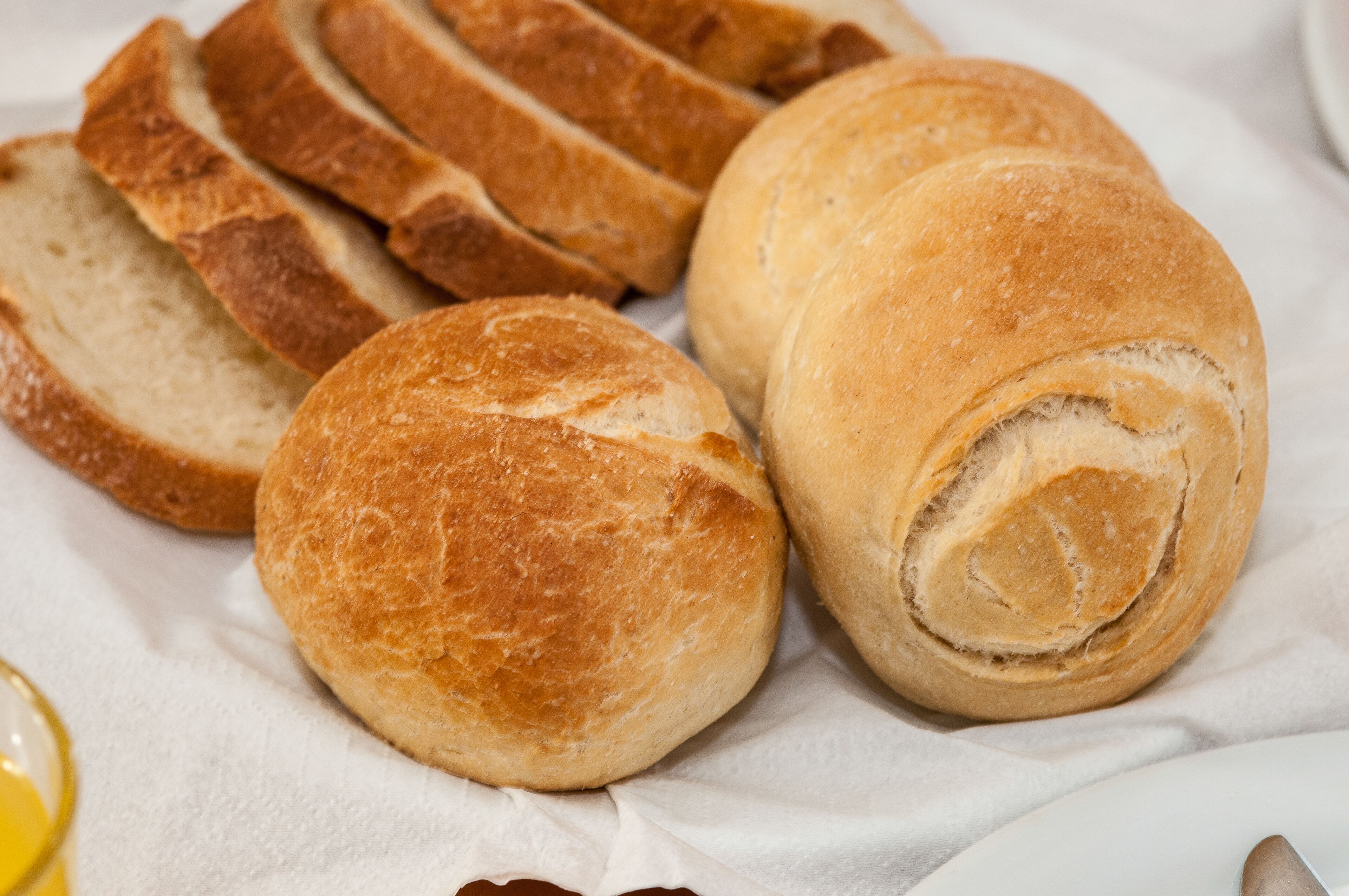 Sliced bread rolls and a whole bread roll on a white cloth.