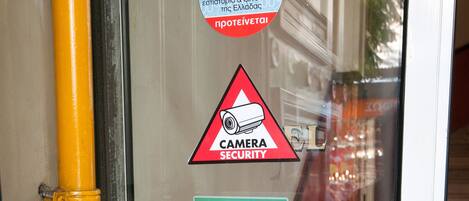 A glass door with various stickers including a camera security warning, TripAdvisor logo, and payment options like Mastercard and Visa.